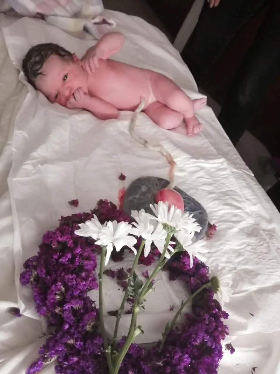 A newborn baby beside flowers and the placenta