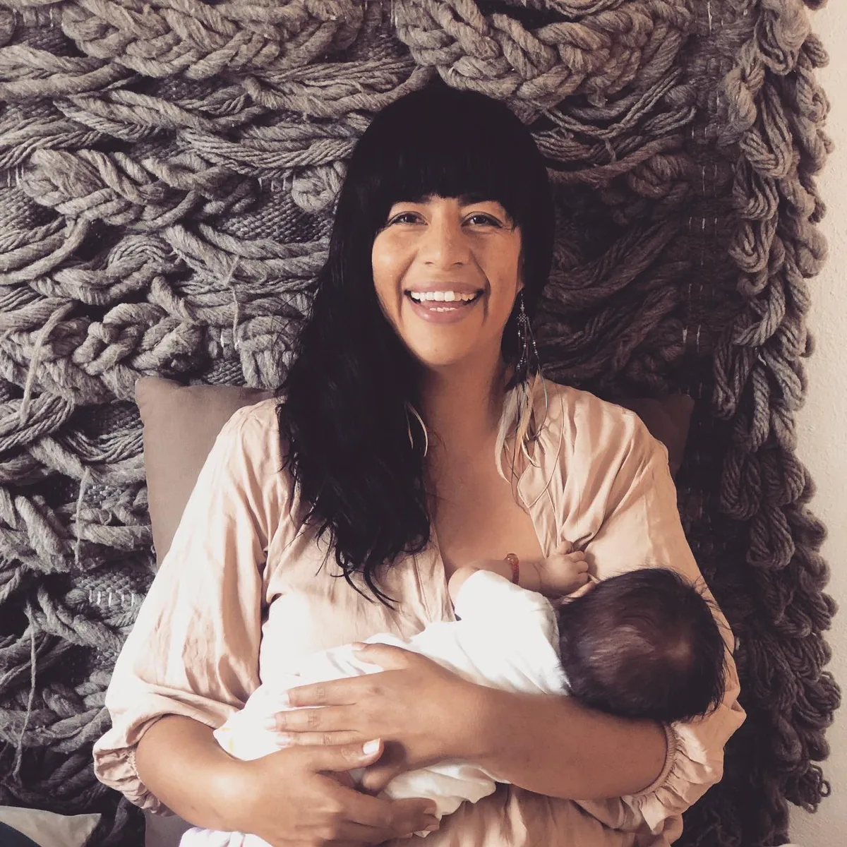 Eine Mutter lächelt, während sie ihr Baby stillt